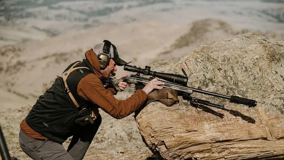 Competitor using a bag and bipod to support a rifle on a rock
