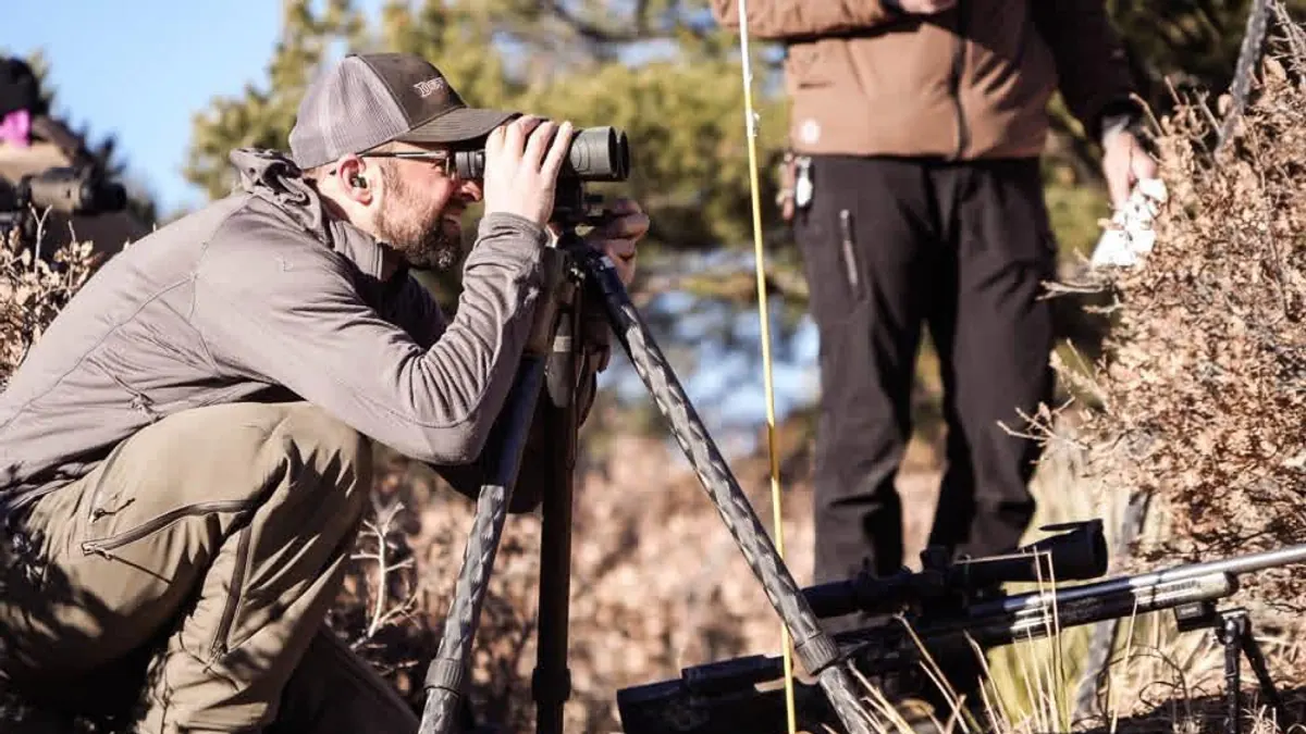 Competitor glassing with binoculars from a field position